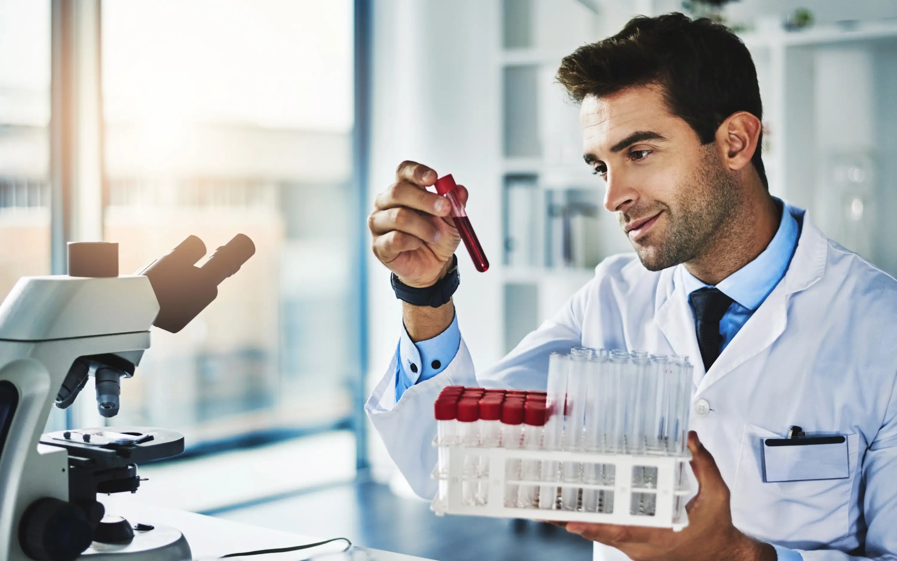 Scientist holding a test tube and a container of samples in a laboratory setting