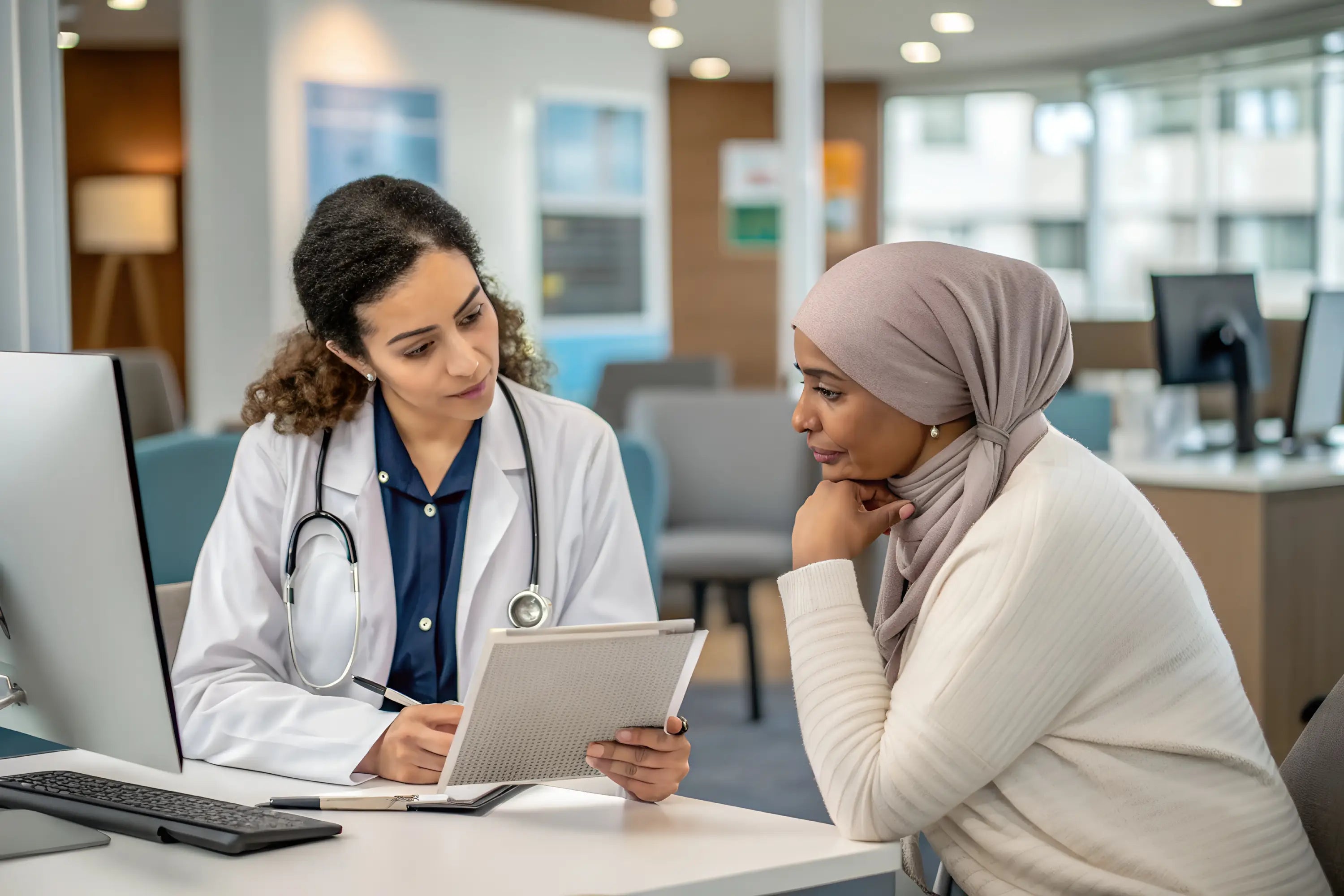 Doctor and patient discussing at a desk in a medical office.