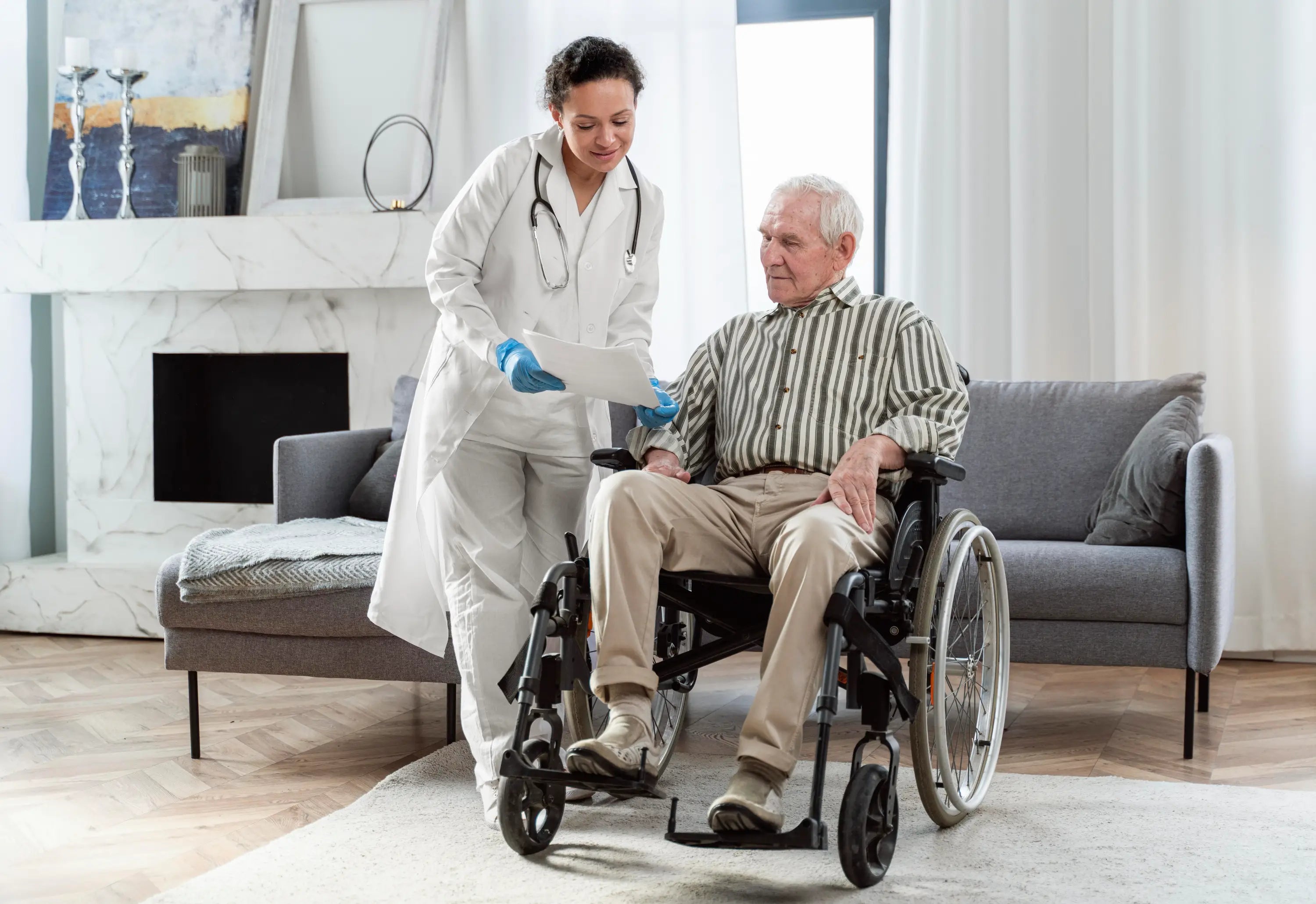 Doctor interacting with an elderly patient in a wheelchair in a home setting.