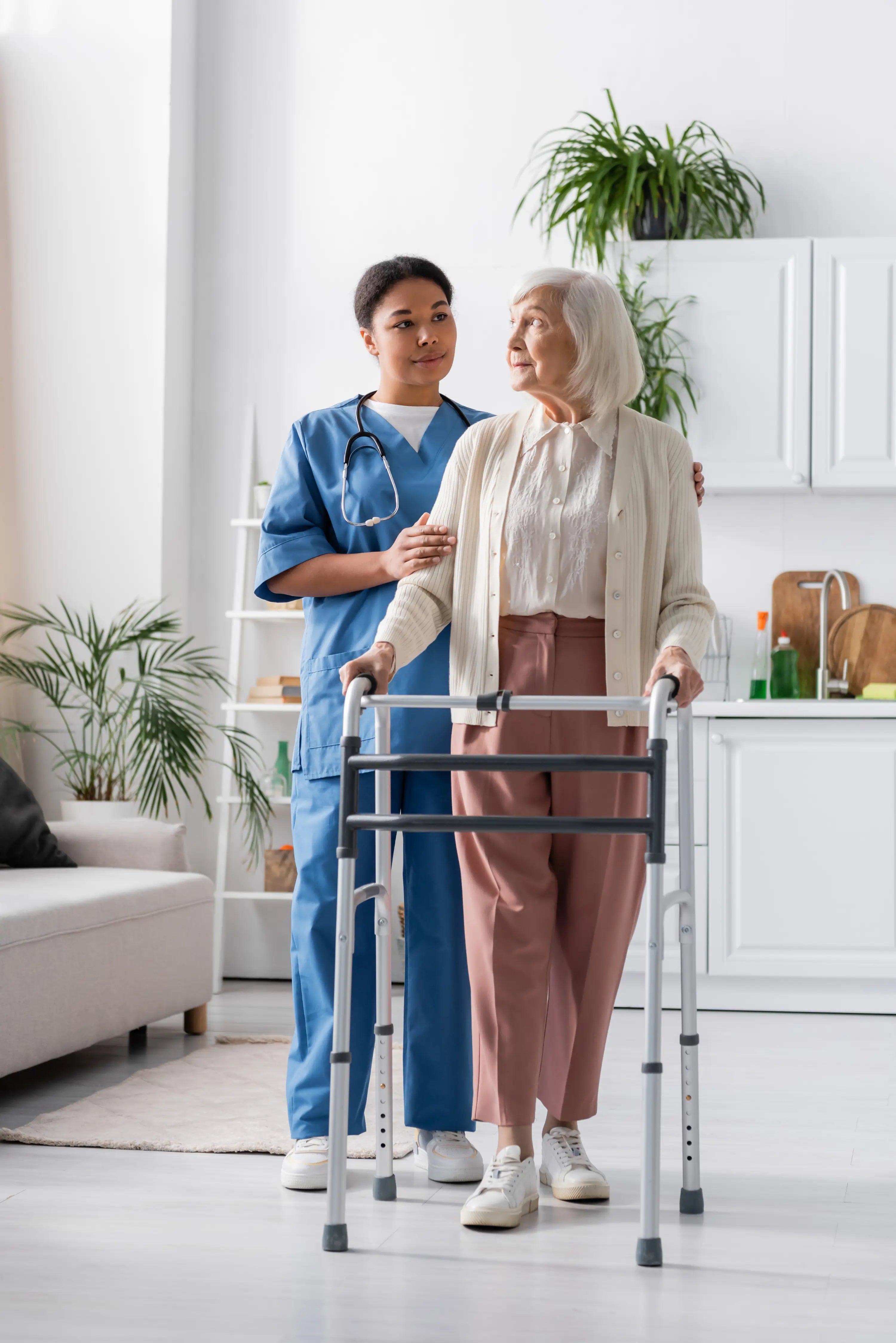 Caregiver assisting an elderly woman using a walker in a home setting