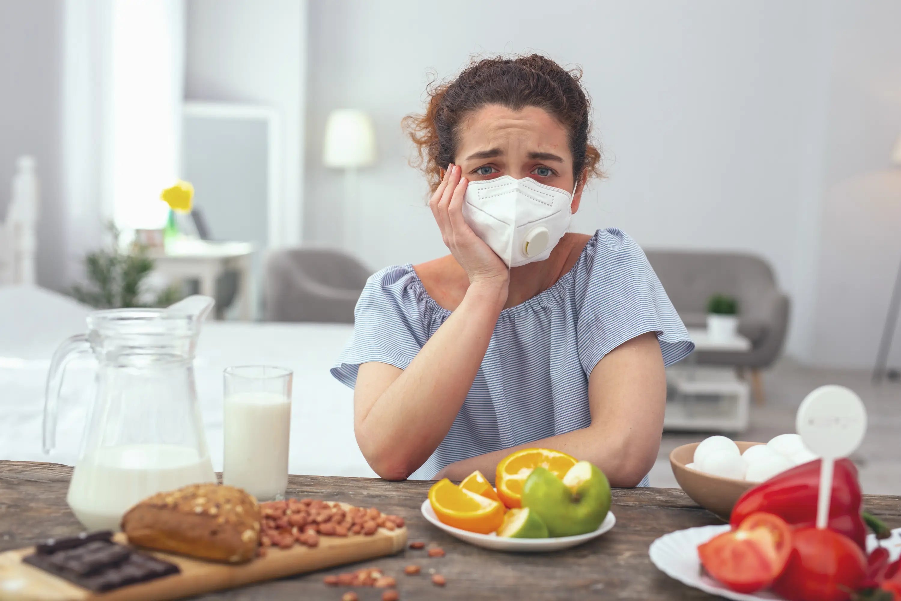 Woman wearing a face mask in a kitchen with food items on the table