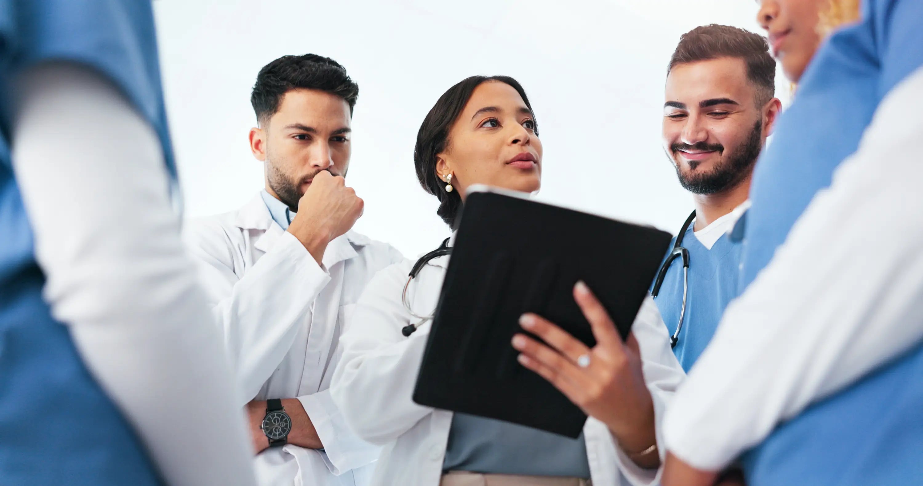 Group of medical professionals in a discussion, with one holding a tablet.