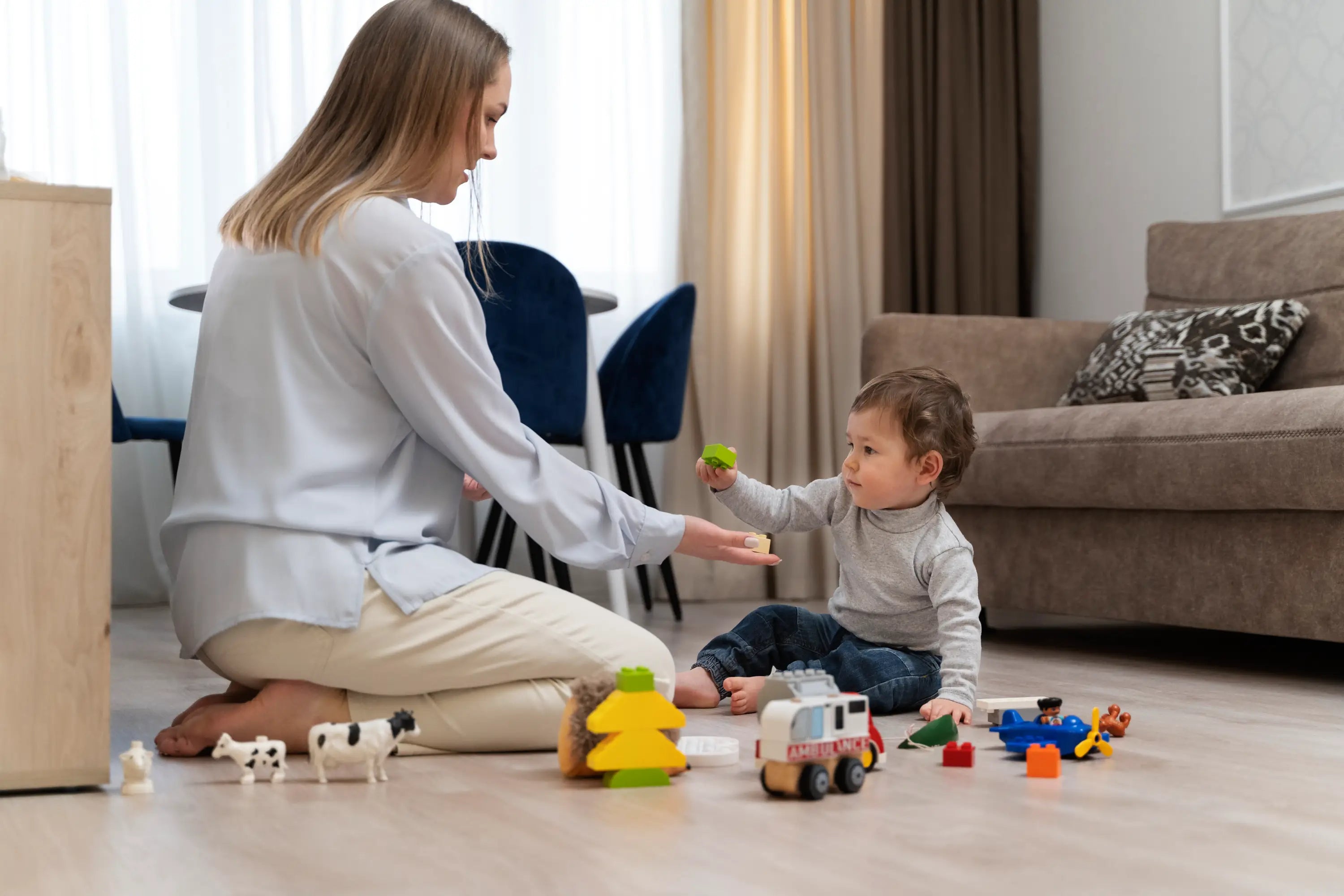 Woman and child playing with toys on a living room floor.