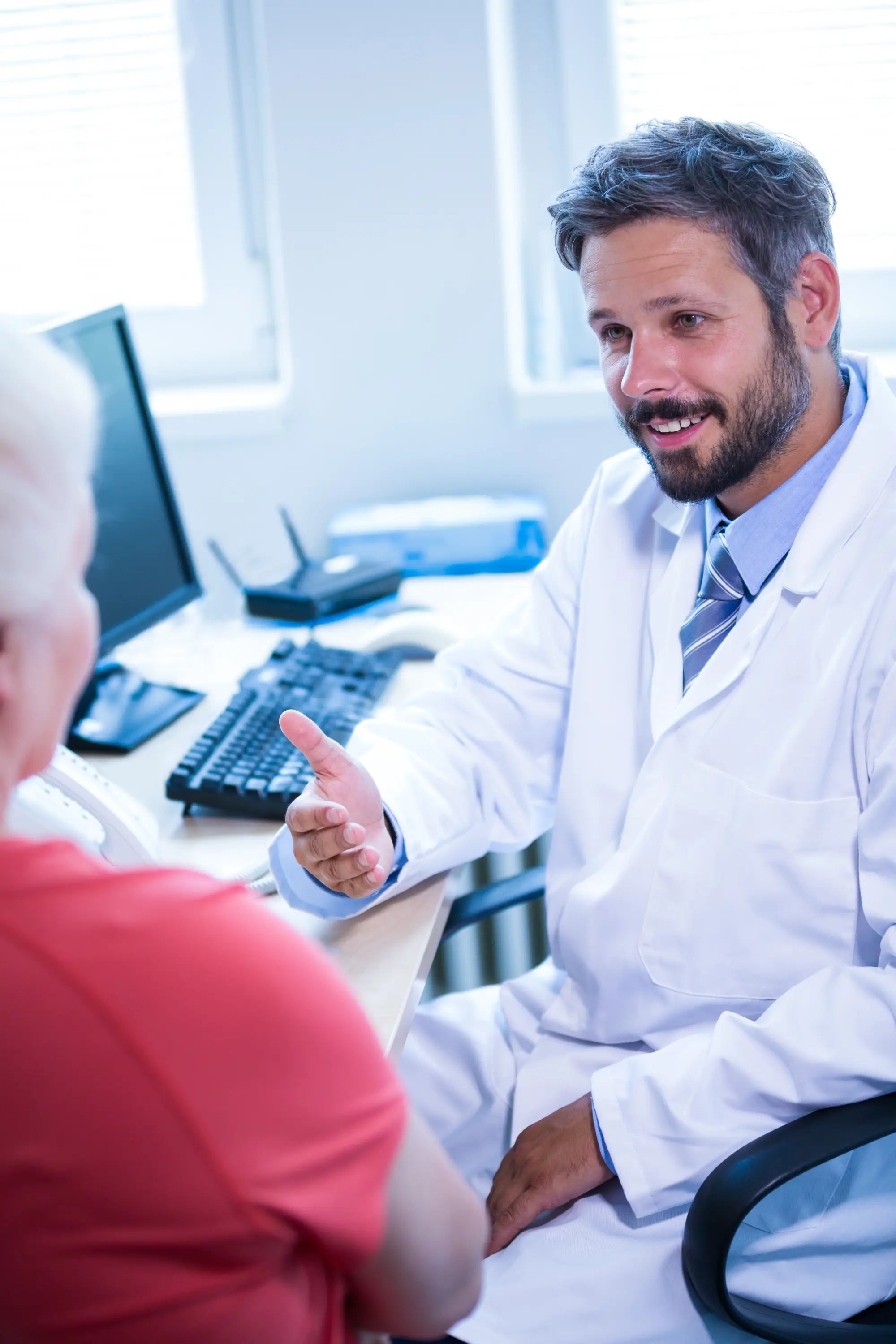 Doctor in a white coat talking to a child in a medical office setting