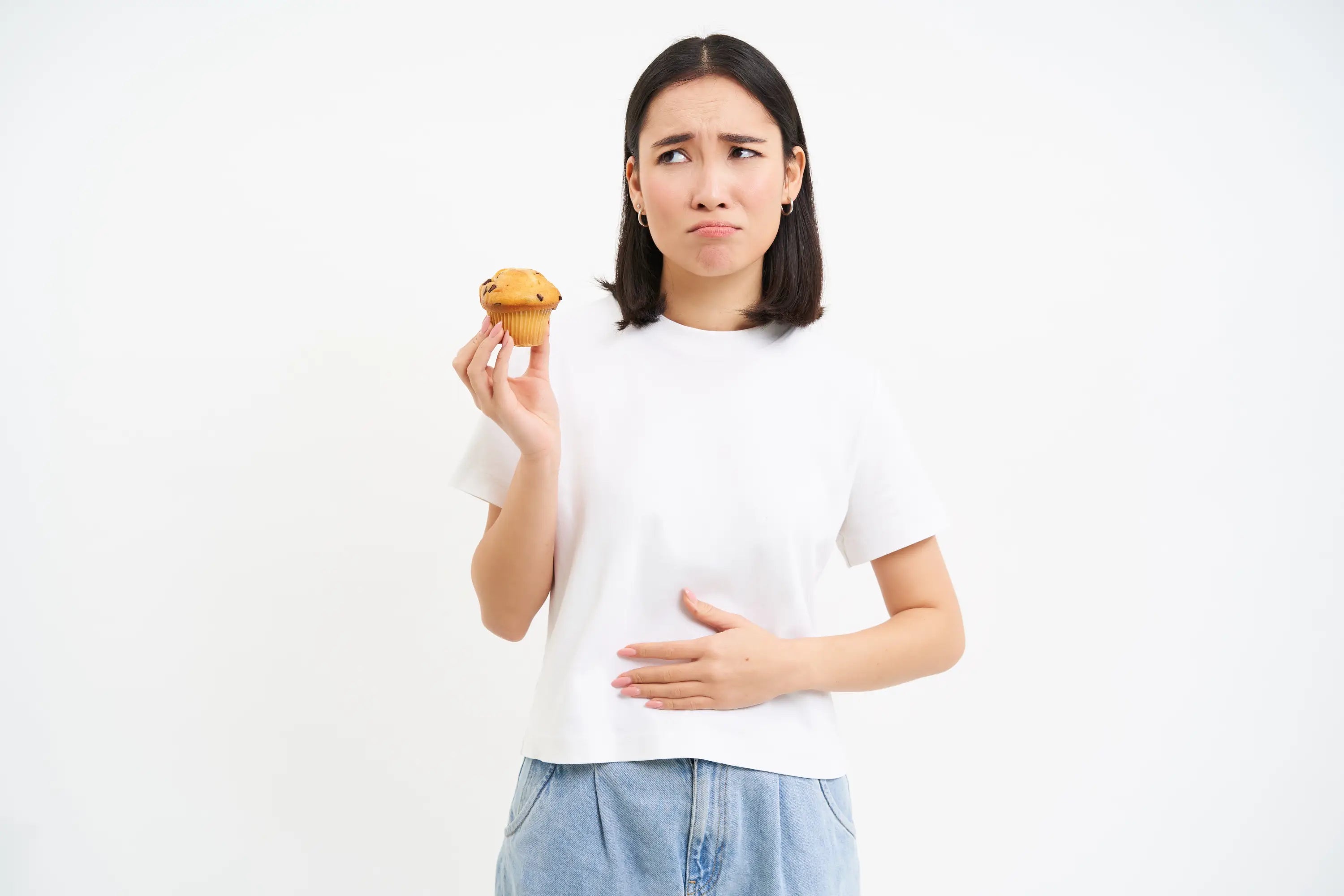 Woman holding a muffin with a concerned expression, possibly about to eat it.