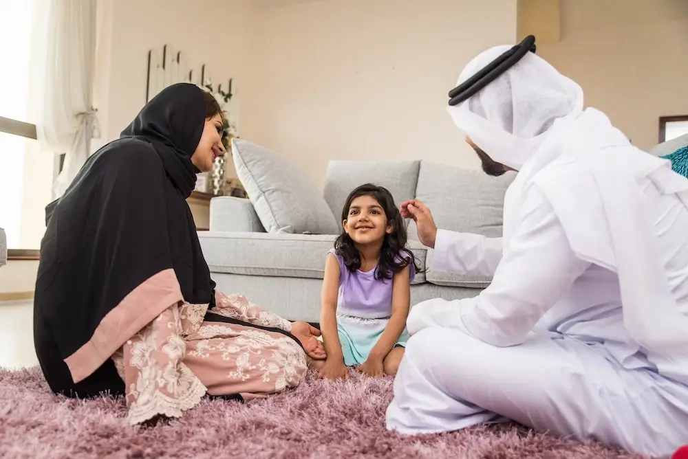 Qatar family spending quality time together at home, sitting on a rug in the living room