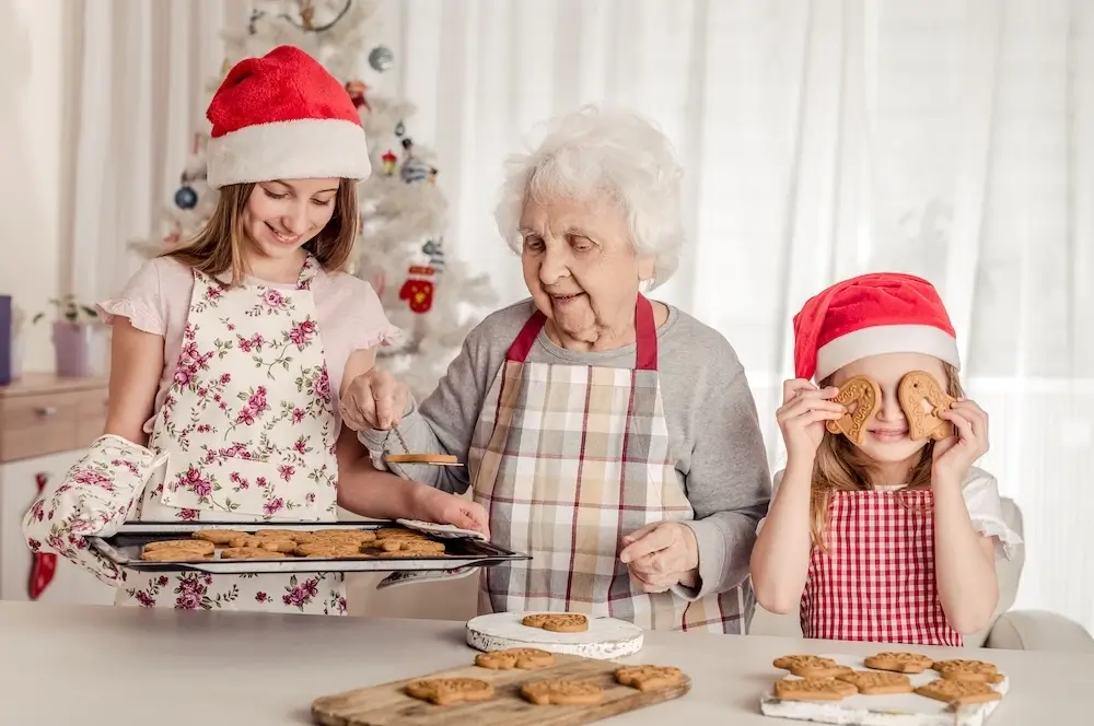 Grandmother baking cookies with her granddaughters during the holidays, symbolizing joyful family moments