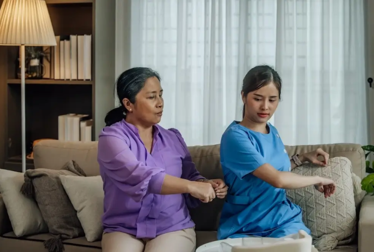 Caregiver assisting an elderly woman with arm exercises at home