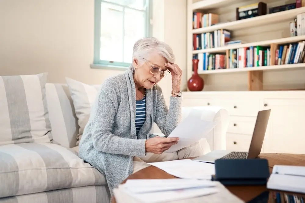 Senior woman reviewing documents at home, reflecting financial or healthcare planning for seniors