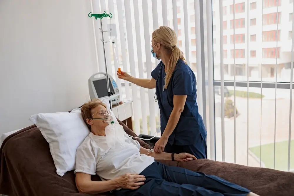 Nurse providing care to a patient receiving oxygen therapy in a medical facility.