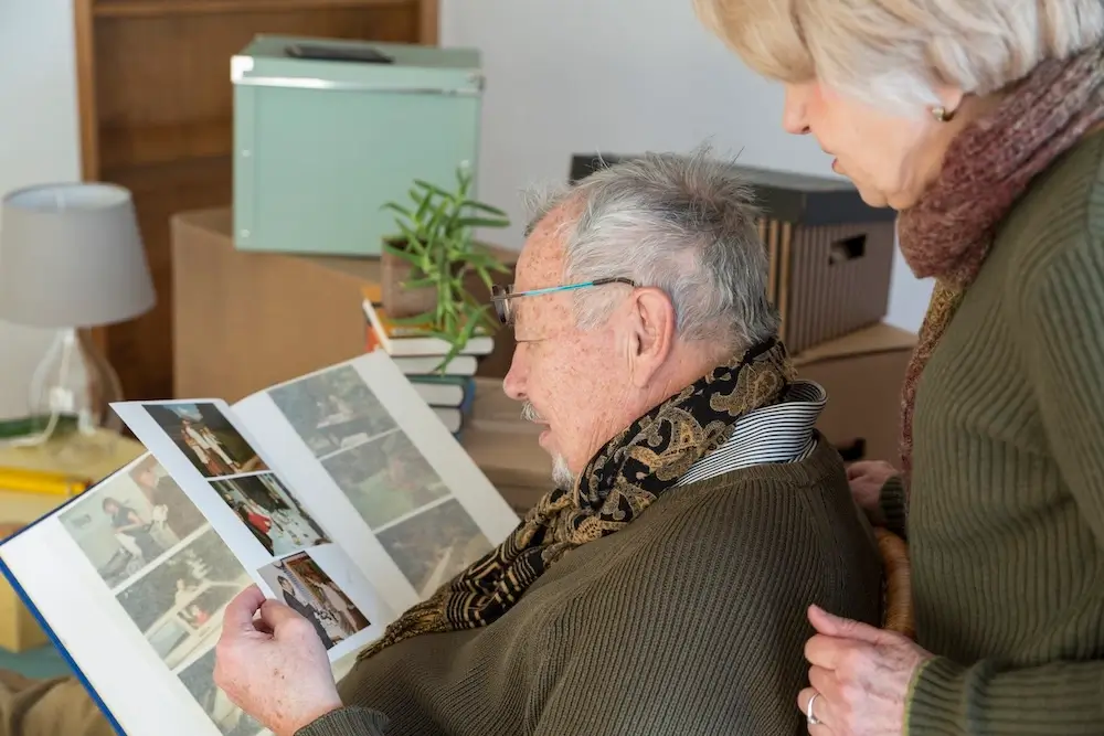 Senior couple looking at a photo album, reflecting on cherished memories in a comfortable home environment