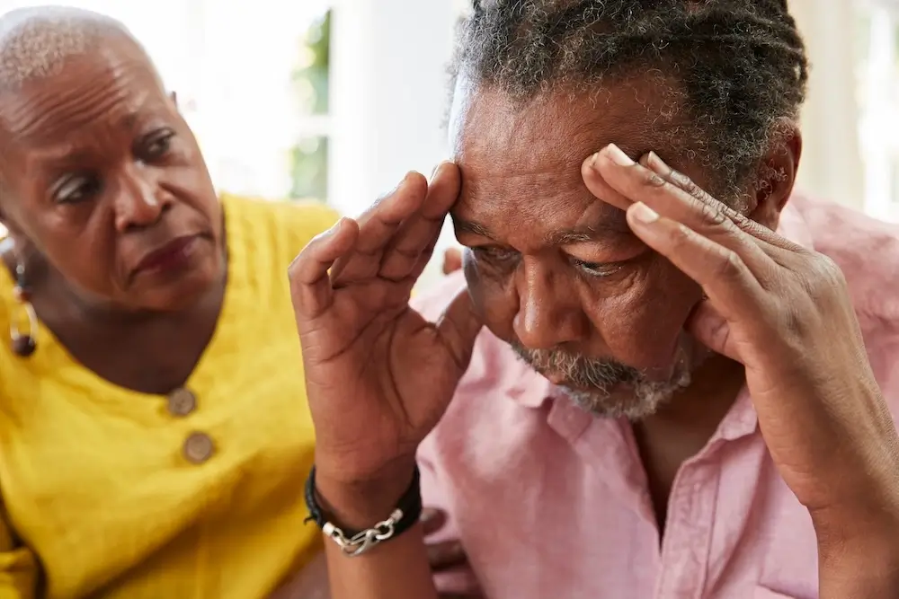 Senior woman comforting a distressed man at home, symbolizing emotional support and care for seniors