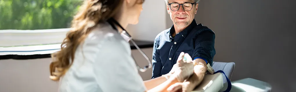 Male patient receiving a blood test in a medical setting with a healthcare professional.