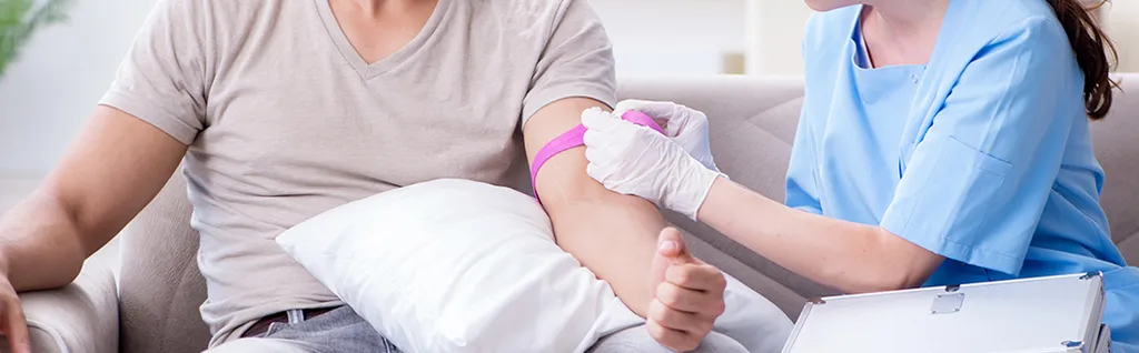 Healthcare professional preparing to draw blood from a patient seated comfortably.